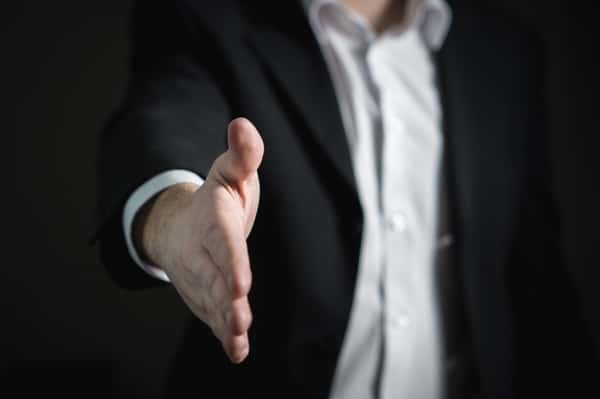 man in business suit holding out his hand for a hand shake